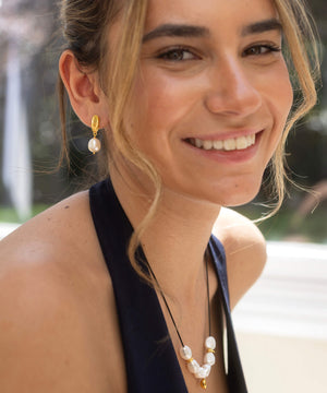 Woman wearing pearl earrings and necklace with blurred outdoor background