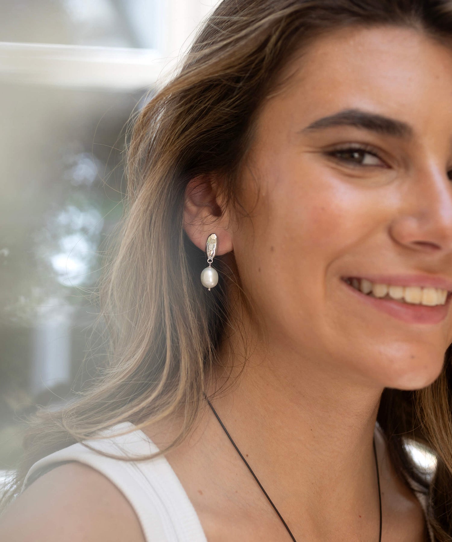 Woman wearing pearl earrings with a blurred background