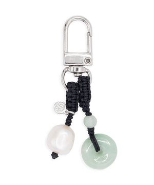 Keychain with black cord, pearl, and jade charm on a white background
