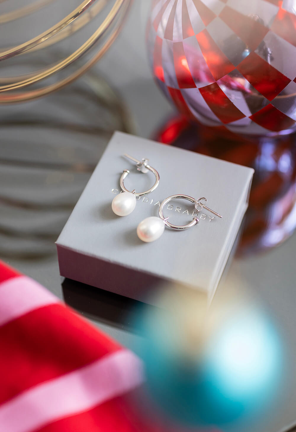 Pair of pearl earrings on a white box with decorative background