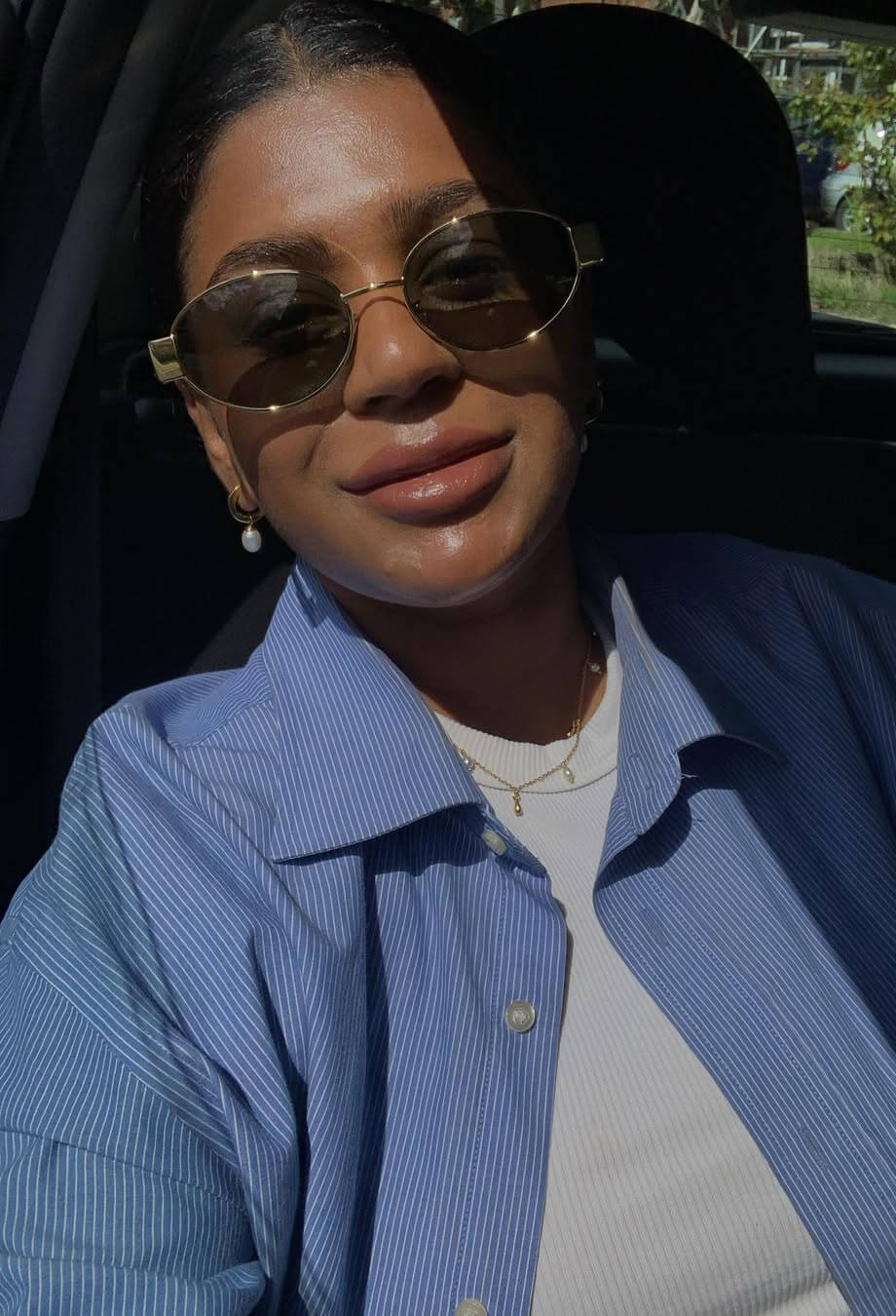 Person wearing sunglasses and a blue jacket inside a vehicle